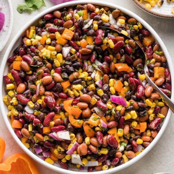 A large Mexican three bean salad with homemade cilantro vinaigrette, in a white bowl ready to serve.