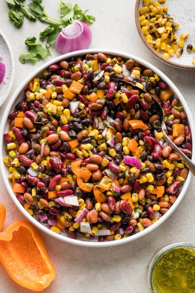 A large Mexican three bean salad with homemade cilantro vinaigrette, in a white bowl ready to serve.