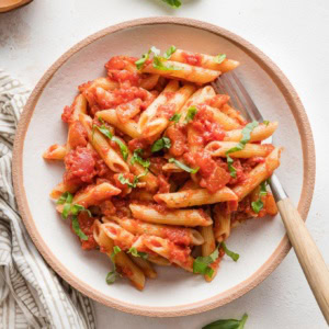 Small wooden bowl filled with a serving of homemade pasta marinara.