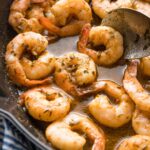 Close up image of jerk seasoned shrimp with sauce in a cast iron skillet.