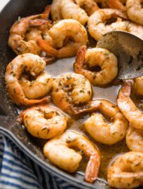 Close up image of jerk seasoned shrimp with sauce in a cast iron skillet.