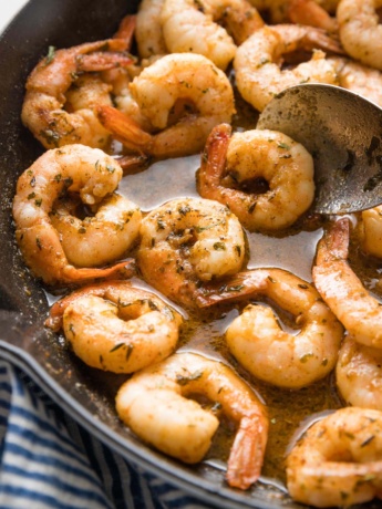 Close up image of jerk seasoned shrimp with sauce in a cast iron skillet.