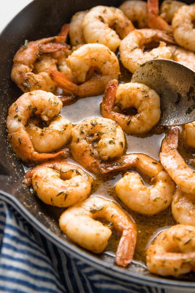 Close up image of jerk seasoned shrimp with sauce in a cast iron skillet.