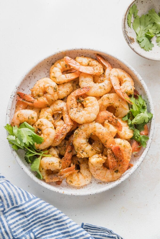 Small white ceramic bowl piled high with jerk seasoned shrimp.