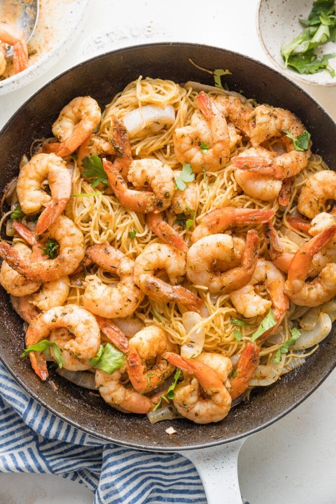 Overhead image of a cast iron skillet full of jerk shrimp pasta, ready to serve.