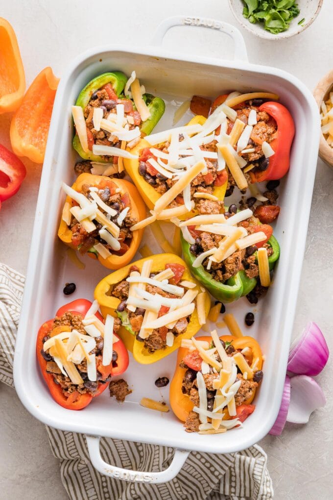 Taco stuffed peppers topped with cheese and ready to bake.
