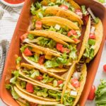 Overhead image of a ceramic baking dish filled with baked tacos.