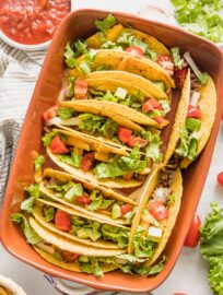 Overhead image of a ceramic baking dish filled with baked tacos.