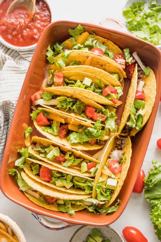 Overhead image of a ceramic baking dish filled with baked tacos.