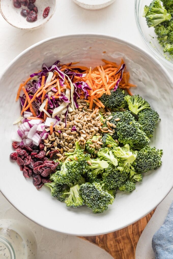 Large bowl containing chopped broccoli, cabbage, carrots, sunflower seeds, and dried cranberries.