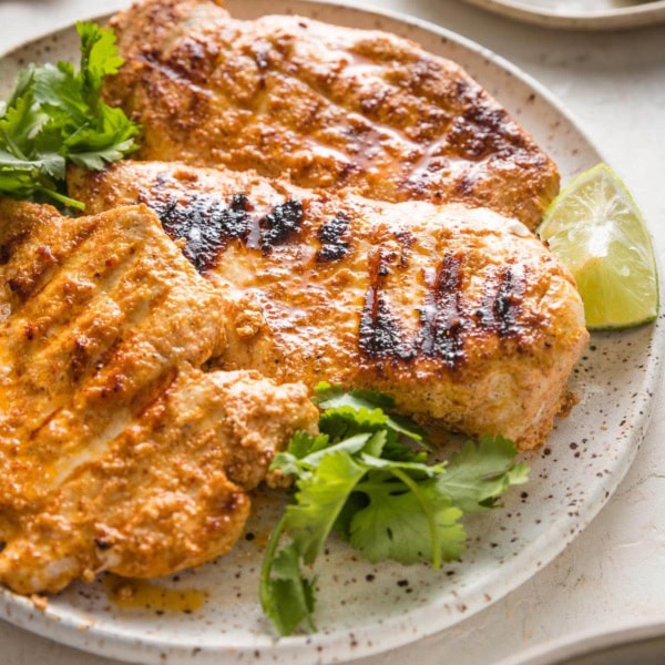 45 degree angle view of a chicken breast cooked with a Baja style marinade with grill marks.