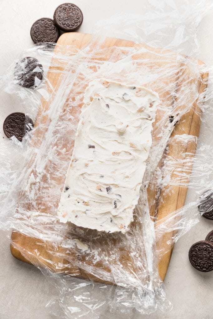 Ice cream cake lifted out of a loaf pan and set on a cutting board.