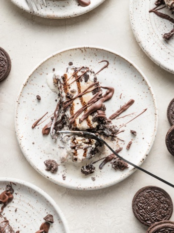 Close up of a fork slicing off a bite of layered Oreo ice cream cake.