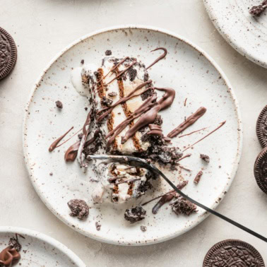 Close up of a fork slicing off a bite of layered Oreo ice cream cake.