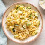 Shallow pasta bowl filled with a helping of pasta with zucchini, corn, and toasted garlicky breadcrumbs.