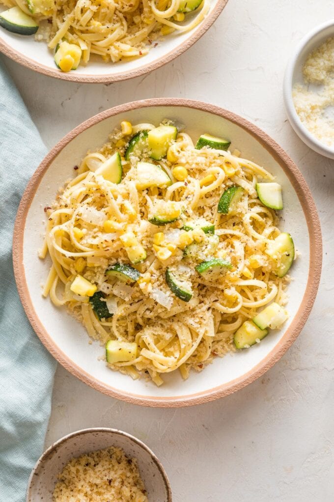 Shallow pasta bowl filled with a helping of pasta with zucchini, corn, and toasted garlicky breadcrumbs.