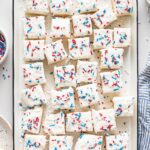 White tray filled with square sugar cookie bars decorated with red white and blue sprinkles for the Fourth of July.