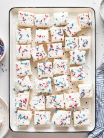 White tray filled with square sugar cookie bars decorated with red white and blue sprinkles for the Fourth of July.