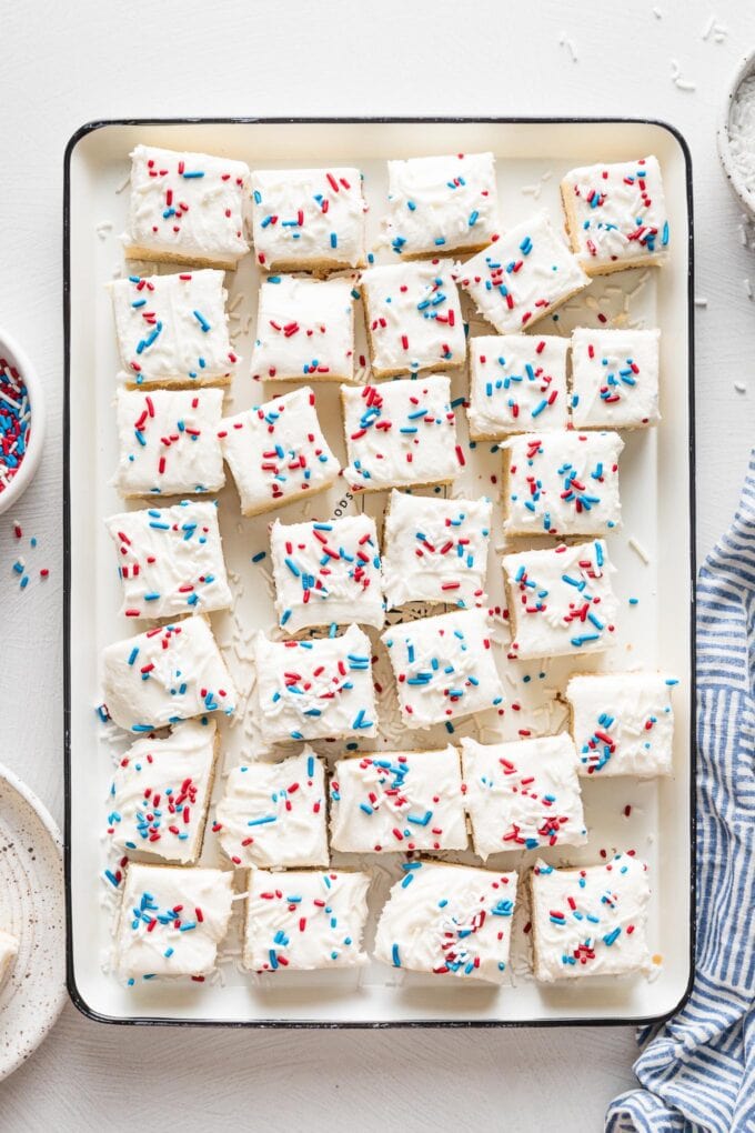 White tray filled with square sugar cookie bars decorated with red white and blue sprinkles for the Fourth of July.