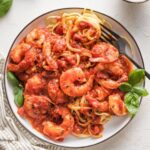 A fork twirling around a serving of shrimp marinara pasta.