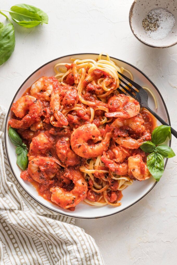 A fork twirling around a serving of shrimp marinara pasta.