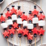 Platter filled with watermelon, blueberry, and marshmallow-laced bamboo skewers.