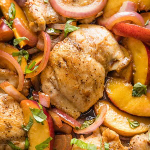 Close up of a chicken thigh cooked with peaches and balsamic vinegar.