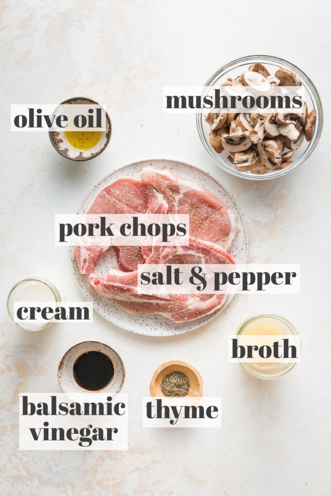 Labeled overhead photo of pork chops seasoned with salt and pepper, sliced baby Bella mushrooms, olive oil, cream, balsamic vinegar, chicken broth, and fresh thyme in prep bowls and on plates.