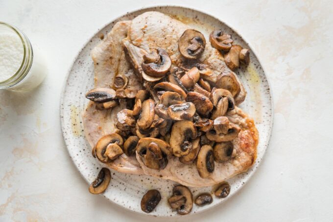 Pork chops and browned mushrooms together on a plate.