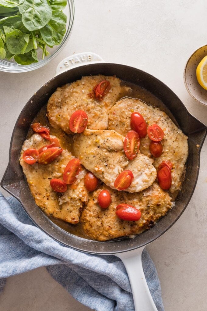 Chicken with burst cherry tomatoes in a white wine pan sauce.