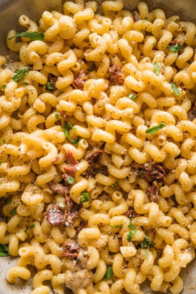 Close up of cavatappi pasta mixed with cream sauce in a skillet.