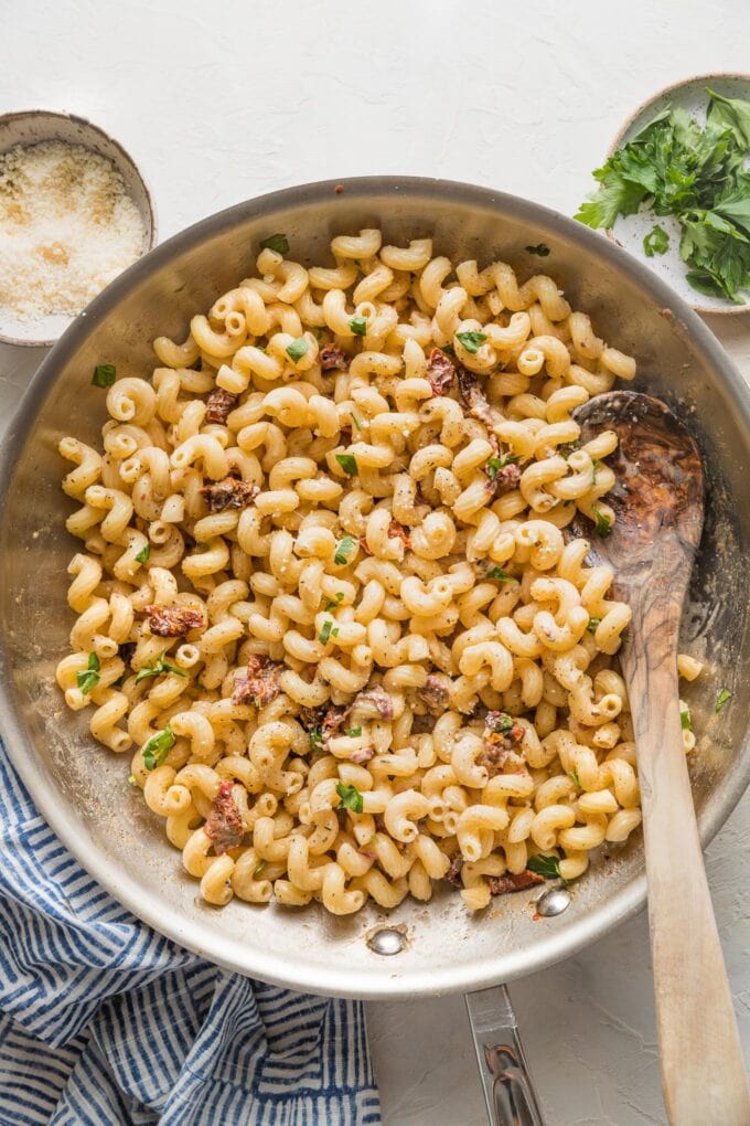 Skillet filled with a creamy cavatappi pasta with Parmesan and sun-dried tomatoes.