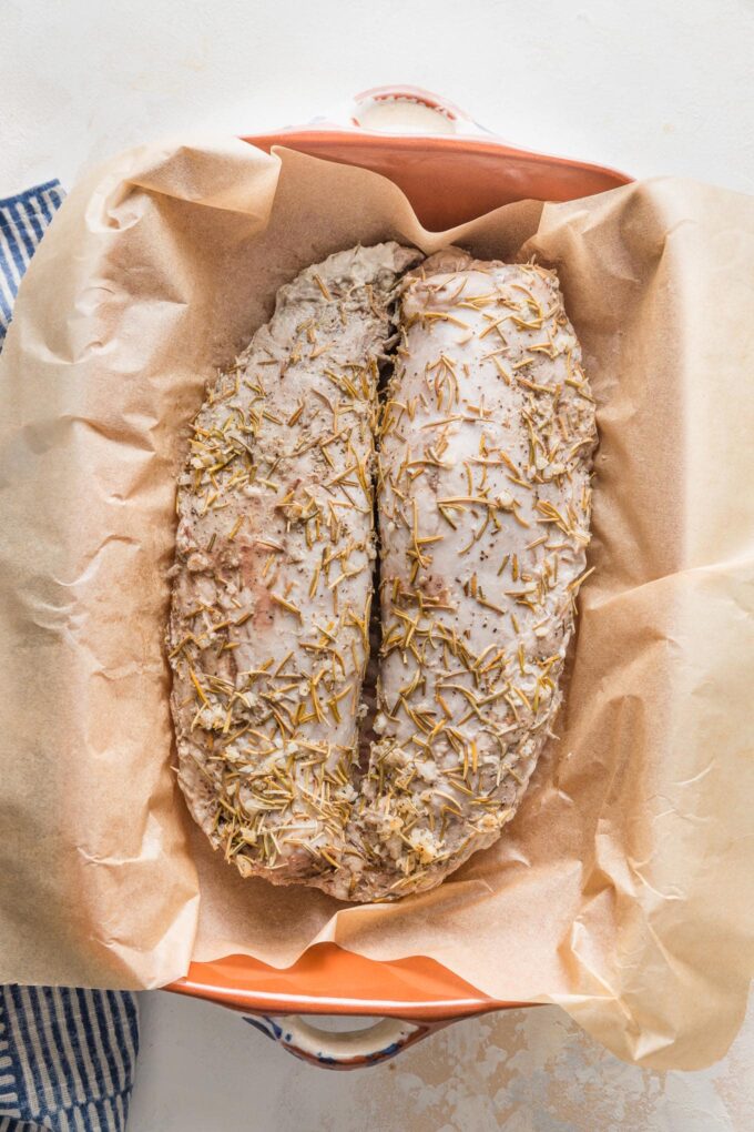 Pork tenderloins removed from the Crockpot and placed in a parchment paper-lined baking pan.
