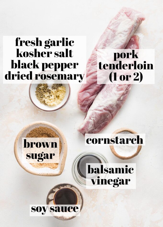 Labeled overhead photo of two pork tenderloins; a spice rub of fresh garlic, dried rosemary, kosher salt, and black pepper; brown sugar; balsamic vinegar; soy sauce; and cornstarch measured into prep bowls and ready to cook.