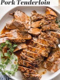 Pork tenderloin cooked with a balsamic glaze, sliced into medallions, and presented on a platter with a garnish of fresh oregano.