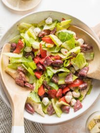 Large white bowl full of a tossed Italian antipasto salad.