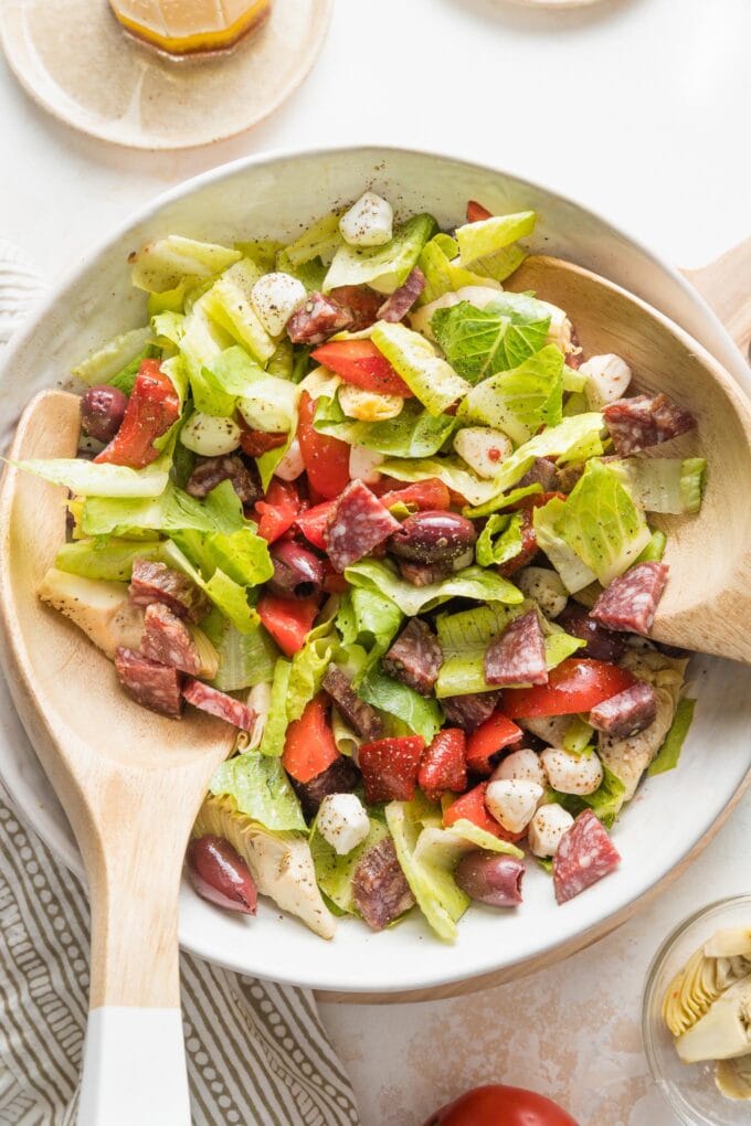 Large white bowl full of  a tossed Italian antipasto salad.