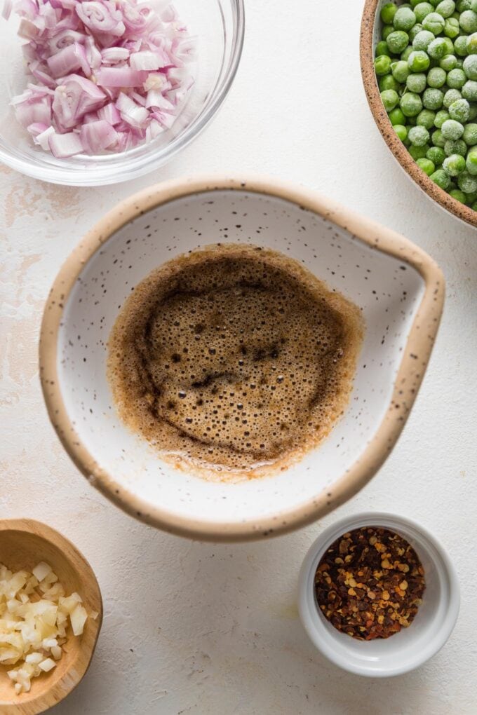 Close up of darkly browned butter in a small white prep bowl.