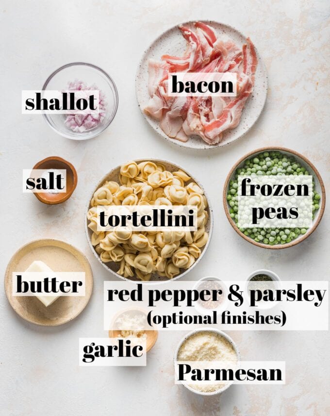 Labeled overhead photo of refrigerated cheese tortellini, slices of bacon, frozen peas, chopped shallot, salt, butter, garlic, red pepper, parsley, and grated Parmesan measured into prep bowls and ready to cook.