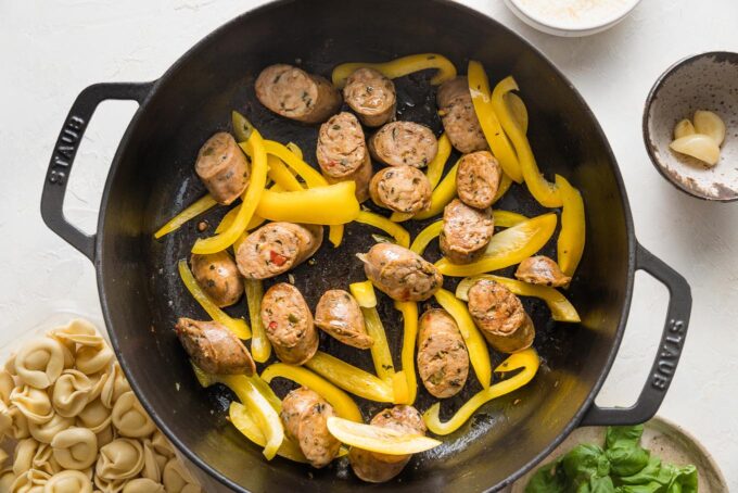 Pan fried sliced Italian sausage and bell pepper strips in a skillet.