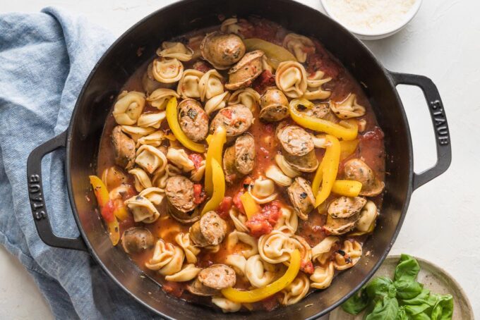 Diced tomatoes, broth, and seasoning added to skillet with sausage and peppers.