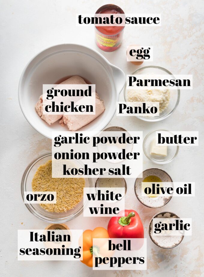 Labeled overhead photo of ground chicken, tomato sauce, grated Parmesan, Panko breadcrumbs, minced garlic, butter, olive oil, 2 bell peppers, Italian seasoning, uncooked orzo, white wine, garlic powder, onion powder, and kosher salt, all measured into prep bowls and ready to cook.