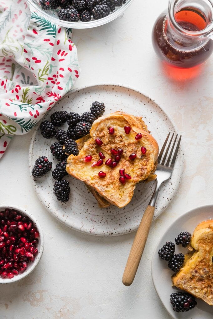 Golden French toast with berries on a plate with a fork.