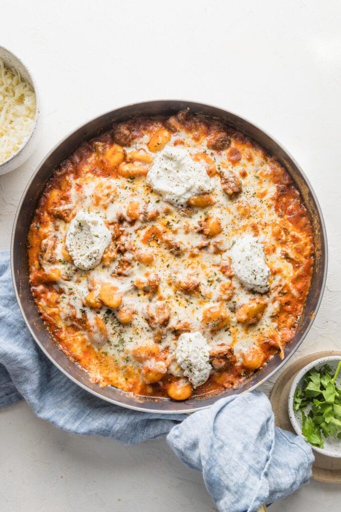 Overhead view of a pan full of ground beef baked gnocchi with a creamy tomato sauce, mozzarella and ricotta cheese, and a bit of fresh parsley.
