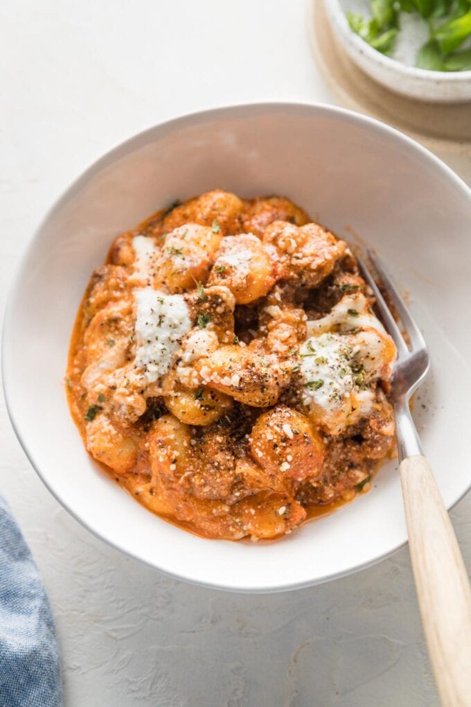 Small bowl filled with a portion of baked gnocchi with ground beef, mozzarella, and ricotta cheese.