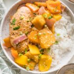 Bowl full of slow cooker pineapple chicken served with white rice, green onions, and sesame seeds.