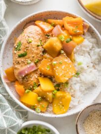 Bowl full of slow cooker pineapple chicken served with white rice, green onions, and sesame seeds.