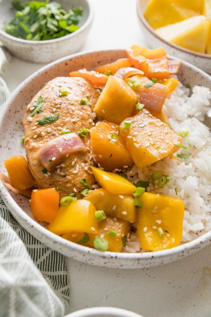 Angled view of a small bowl filled with a generous helping of Crockpot pineapple chicken.