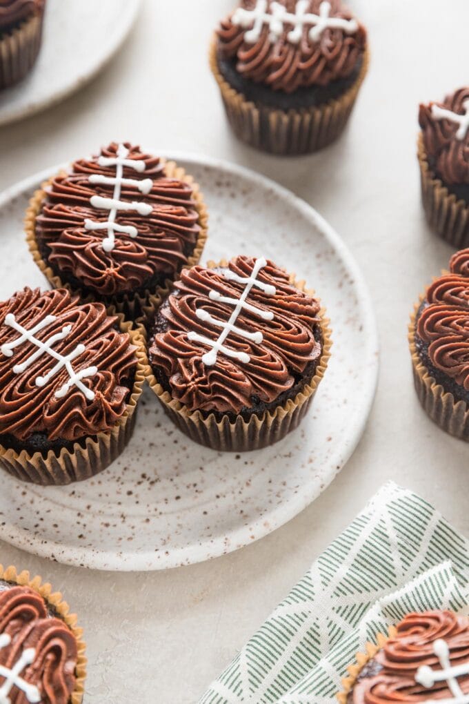 Angled view of a cupcake decorated to look like a football with chocolate frosting and white buttercream 