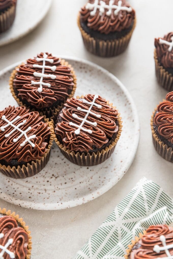Angled view of a cupcake decorated to look like a football with chocolate frosting and white buttercream "laces."